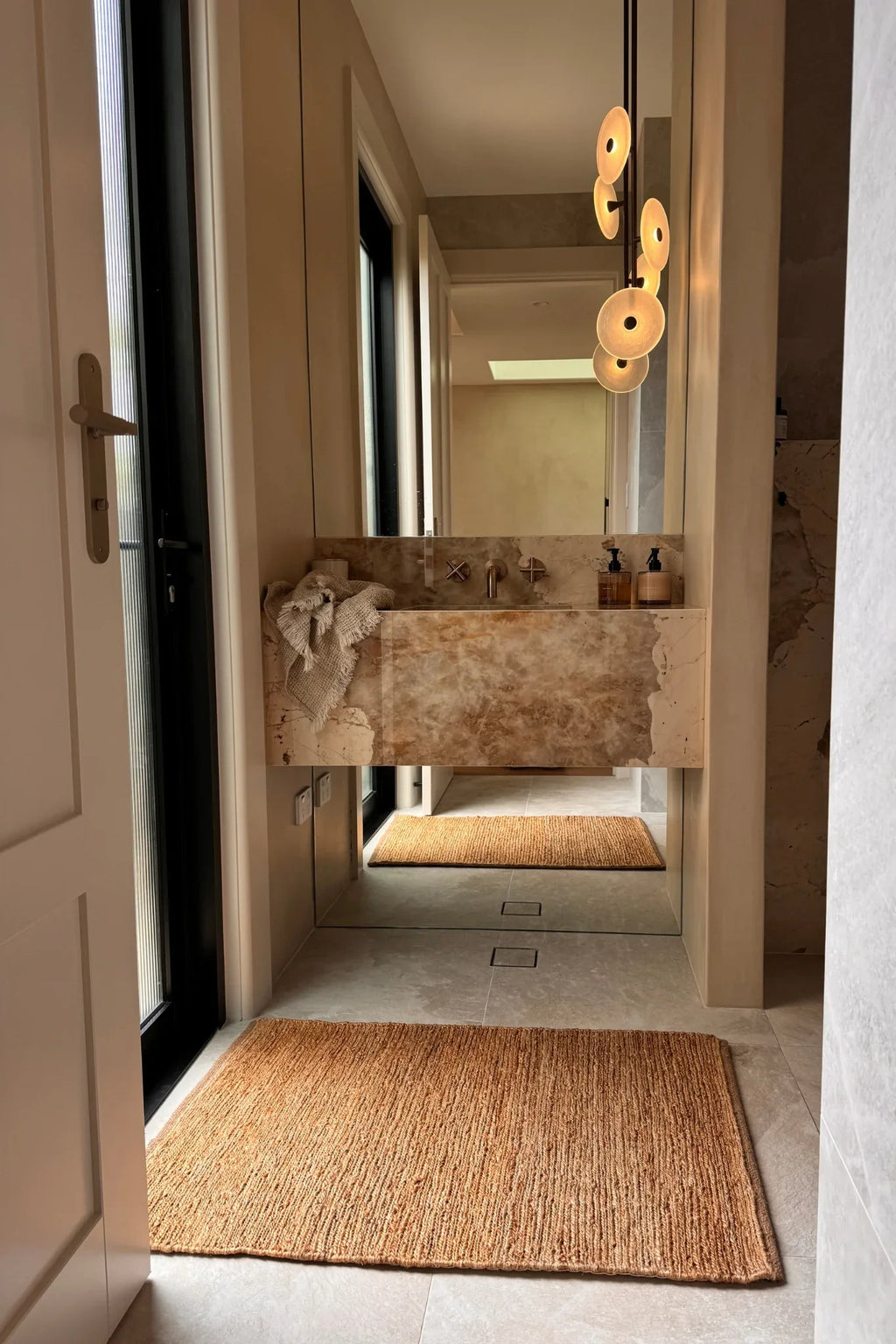Bathroom interior with a stone sink and jute floor mat.