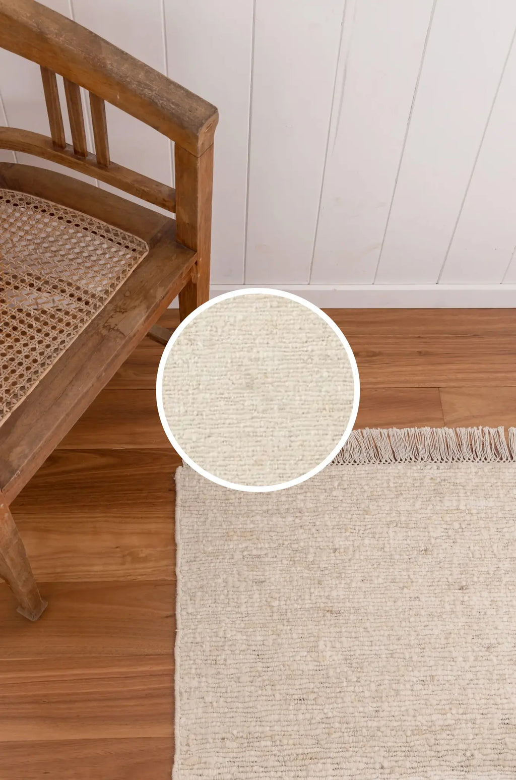 Close-up of a textured beige rug with a wooden chair on a wooden floor.